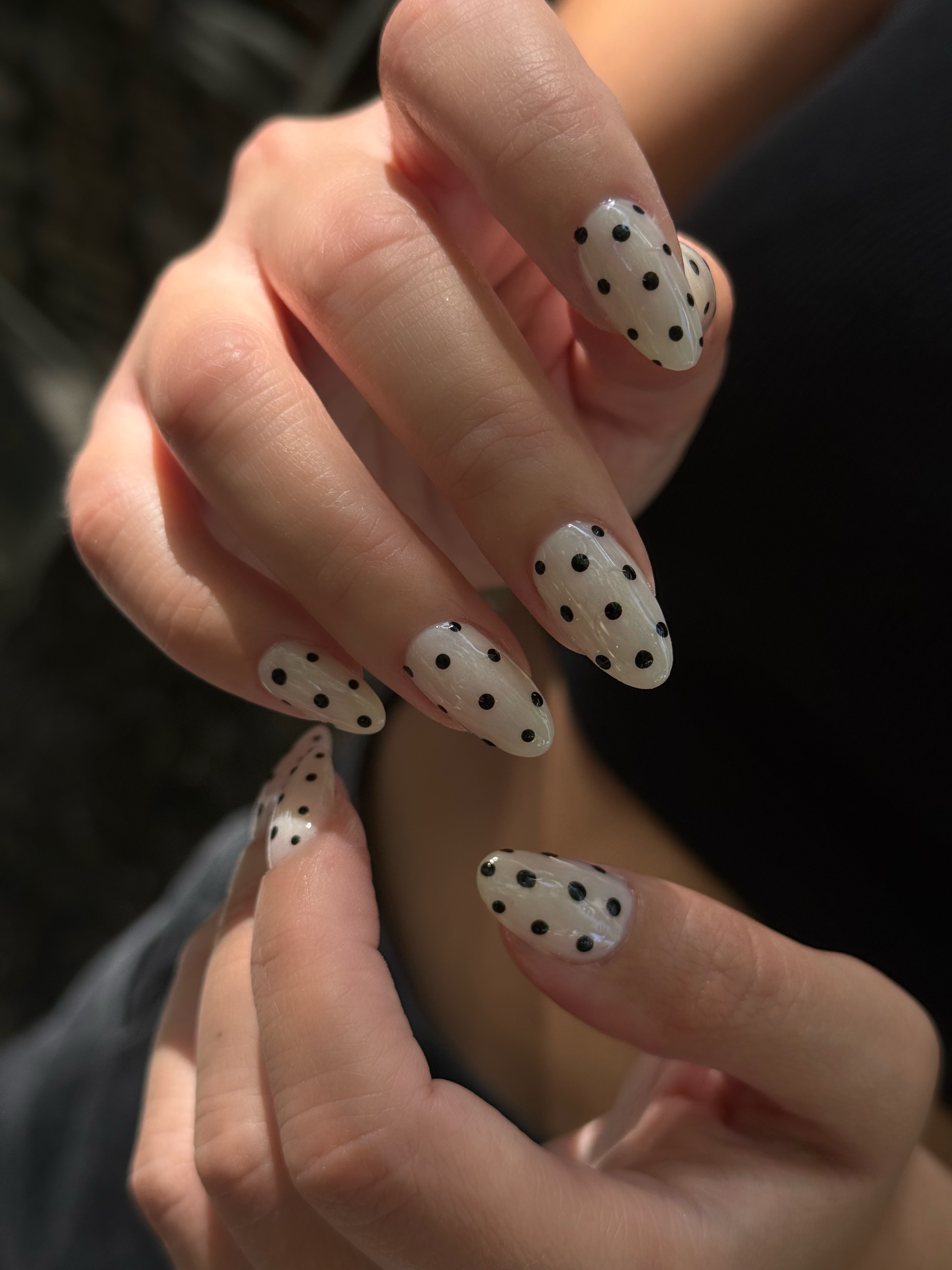 Chic black polka dot nail art on clear gel base with almond shape in Sunnyvale